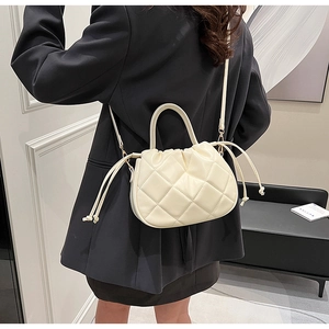 Detail view of cream quilted PU crossbody bag with drawstring closure and top handle
