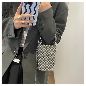 Détail du sac bandoulière en perles argentées avec chaîne sur un blazer gris chic