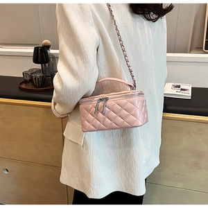 Detail of pink quilted matte leather box bag with gold-tone chain strap worn on white blazer