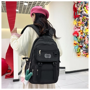 Vue détaillée du sac à dos en nylon noir avec plusieurs poches et fermetures éclair argentées