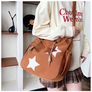 Dettaglio di borsa a tracolla in nylon marrone con toppe a stella e chiusura con coulisse