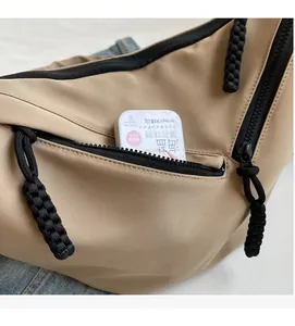 Detail view of the khaki nylon crossbody bag front zipper pocket with storage space