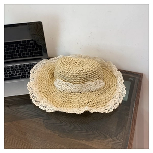 Detail of hand-woven straw hat with elegant white lace trim on a dark wooden surface