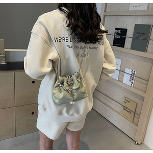 Detail of light green glossy bucket bag with silver handle and pearl charm for women