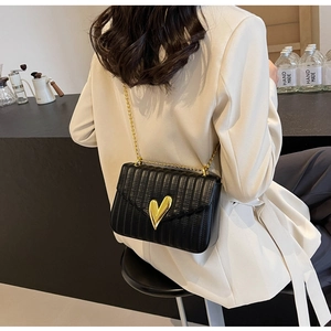 Detail of black quilted PU bag featuring a golden heart lock and elegant chain strap