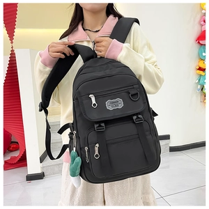 Détail d'un sac à dos en nylon noir avec étiquette mode et pendentif en peluche vert