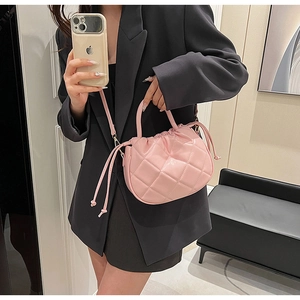 Detail view of pink quilted PU leather crossbody bag with drawstring closure worn by model