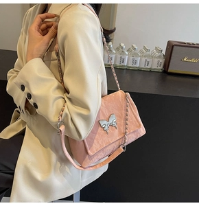 Détail du sac en cuir verni plissé rose avec boucle papillon argentée et bandoulière