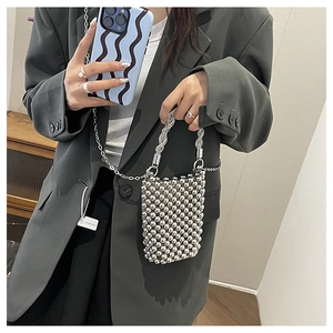Détail d'un mini sac perlé argenté avec poignée tressée et bandoulière en chaîne fine