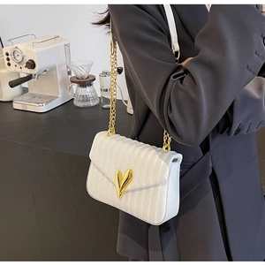 Detail of white quilted PU leather bag with gold heart-shaped twist lock and chain strap