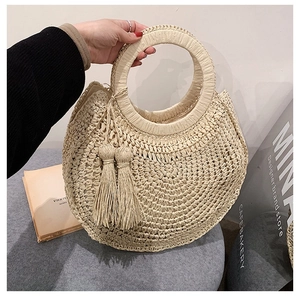 Beige round straw handbag with circular handles and fringe tassels in boho style