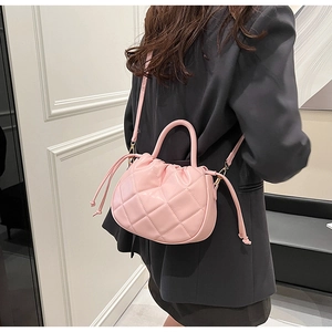 Detail of pink quilted PU leather crossbody bag with drawstring closure on a model