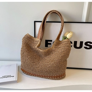 Handwoven straw tote bag with brown scalloped leather trim and long shoulder straps