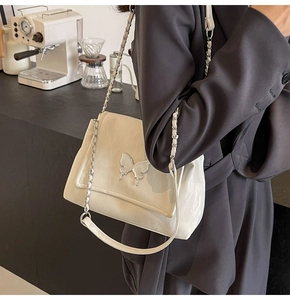 Détail du sac fourre-tout crème en PU avec fermoir papillon argenté et bandoulière chaîne