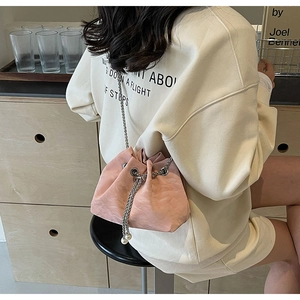 Detail of pink drawstring bucket bag with silver chain and pearl closure on model
