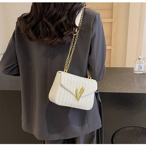 Vertical quilted white PU leather crossbody bag with golden heart clasp shown on a model