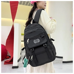 Vue détaillée d'un sac à dos noir en nylon avec poches zippées et breloque peluche