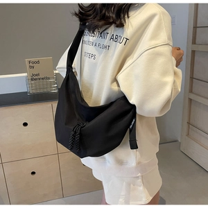 Detail of black nylon crescent crossbody bag with woven zipper pull and brand tag