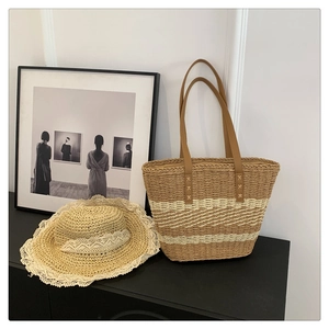Close-up of a woven straw handbag with brown leather straps and matching lace trim straw hat