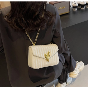 Chic white quilted shoulder bag with golden heart buckle shown on a female model