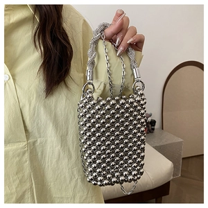 Détail d'un sac à main perlé argenté avec poignée torsadée et fine bandoulière chaîne