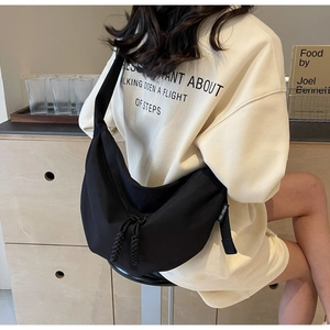 Close-up of black nylon crescent crossbody bag with braided zipper detail on model
