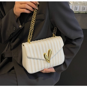 Detail of white quilted PU leather bag with golden heart-shaped buckle and chain strap