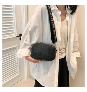 Détail du sac bandoulière noir en cuir PU avec motif rose gaufré et sangle géométrique