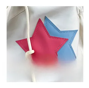 Dettaglio di stelle in pelle rosse e blu su borsa bianca a secchiello con cuciture