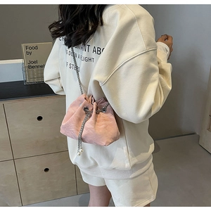 Detail of pink drawstring bucket bag with soft faux leather texture and pearl chain charms
