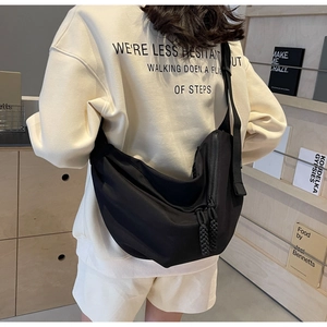 Detail view of black large nylon crescent crossbody bag with wide strap and rope zipper