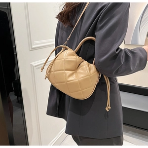 Detail of beige quilted PU crossbody bag shown with adjustable strap and drawstring closure