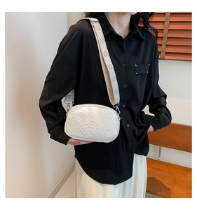Détail du sac à bandoulière en PU blanc avec texture rose et sangle brodée
