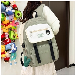 Détail d'un sac à dos en nylon vert pois avec rabat blanc, boucles et pendentif cactus