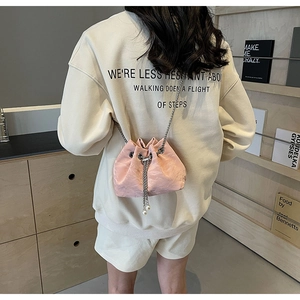 Detail of pink drawstring bucket bag with silver chain strap and white pearl accents