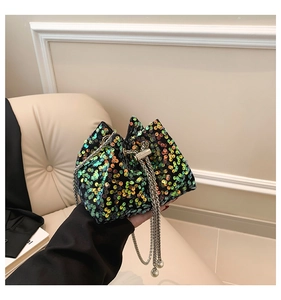 Detailed shot of sparkling green and orange sequin bucket bag with silver chain and pearls
