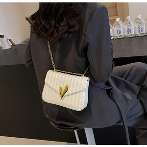 Close-up of white pleated PU leather bag featuring a gold heart-shaped metal clasp