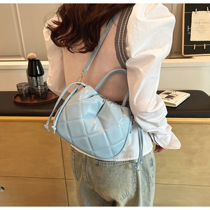 Detail of light blue quilted shoulder bag with drawstring closure and crossbody strap