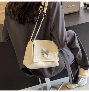 Détail du sac en cuir plissé crème avec papillon en métal argenté et bandoulière