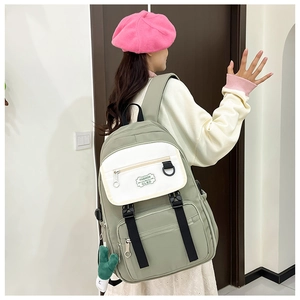 Détail d'un sac à dos en nylon bicolore vert et blanc avec pendentif cactus et boucle robuste