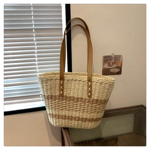 Chic woven straw tote bag with brown straps and white cross stitching for a retro summer look