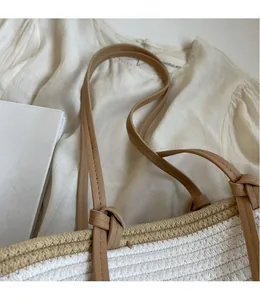 Detail of woven handheld bag with textured pattern and knotted brown leather handle