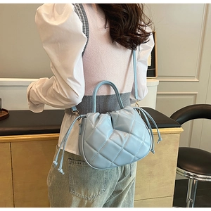 Close-up of a light blue quilted crossbody bag with drawstring details and gold accents