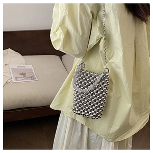 Détail d'un sac à main argenté avec perles métalliques et fine bandoulière chaîne