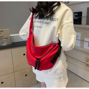 Detail of red crescent canvas crossbody bag with thick black zipper and adjustable strap