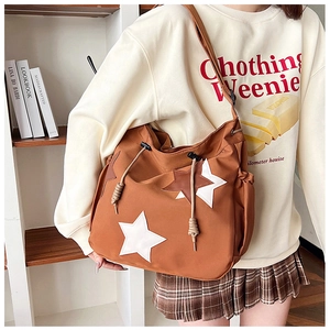Borsa a tracolla marrone in nylon con toppe a stella, portata a spalla in una biblioteca