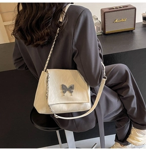 Détail du sac cabas en cuir PU crème avec boucle papillon argentée et bandoulière chaîne