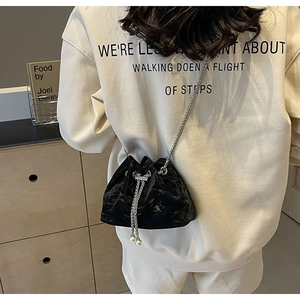 Detail of black pleated bucket bag with pearl drawstring accents and silver chain strap