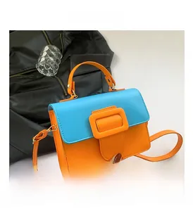 Detail view of the contrasting orange square buckle and premium PU leather flap of the bag