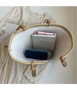 Spacious interior of a woven straw tote bag holding a tablet, books, and essentials